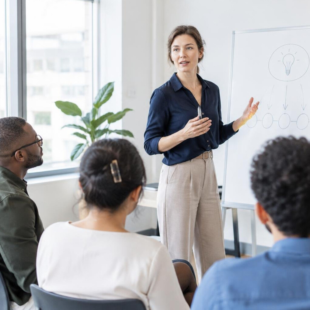 Facilitator leading a discussion with colleagues in a bright meeting room